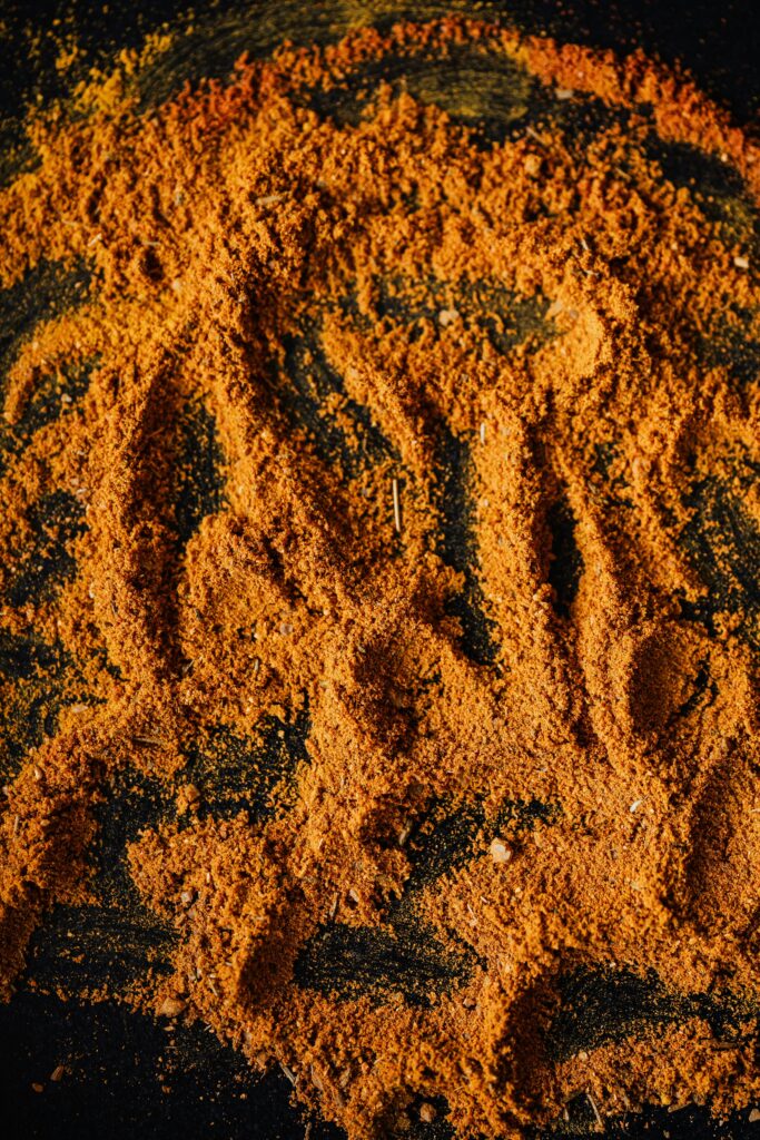 Vibrant mix of dry aromatic spices on black surface, showcasing textures and colors.