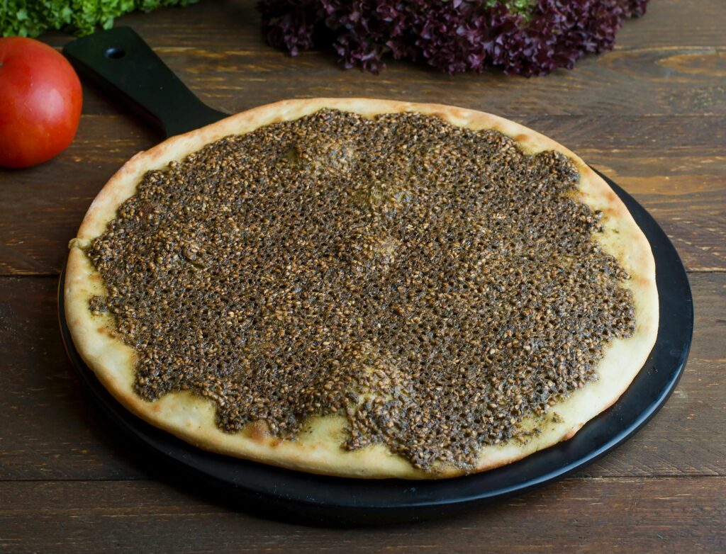 Delicious zaatar manakish on a tray with fresh vegetables on a wooden surface.